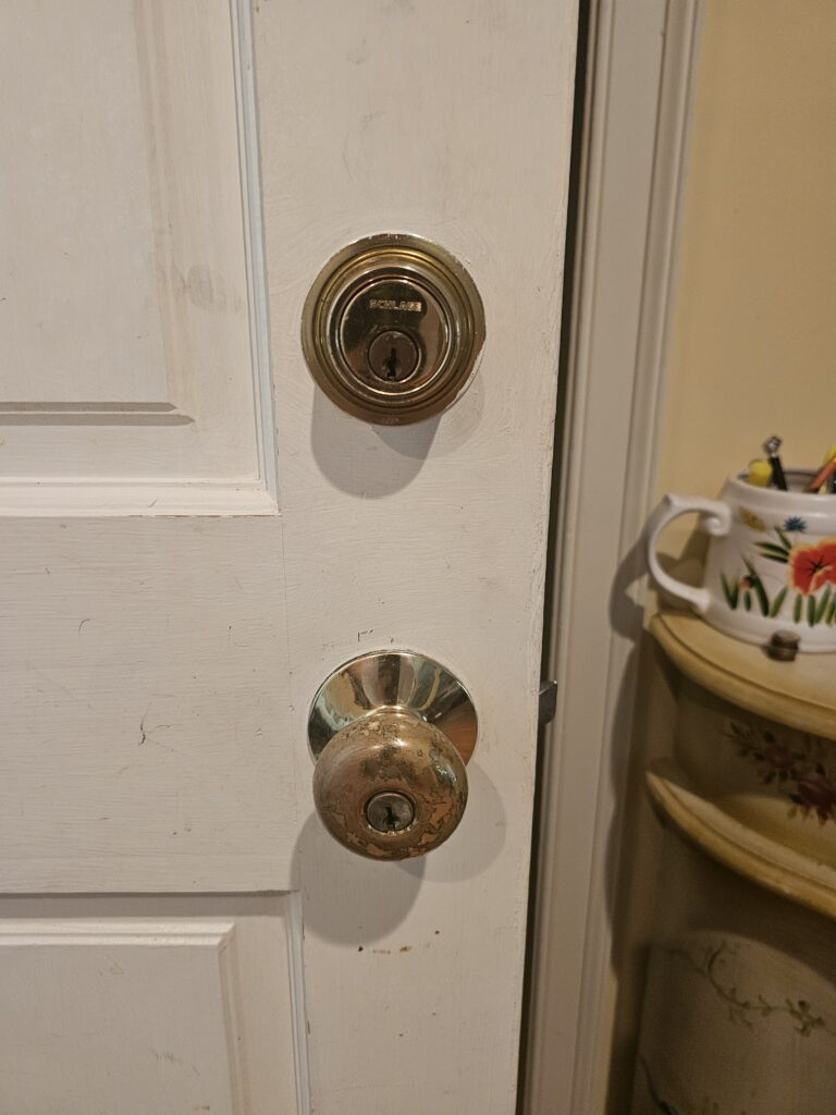 Close-up of brass Schlage deadbolt and handle before rekeying