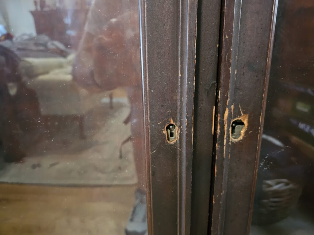 Close-up of dual skeleton keyholes on antique cabinet