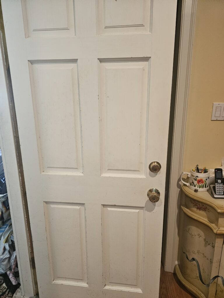 Side garage door with white panel before lock rekeying