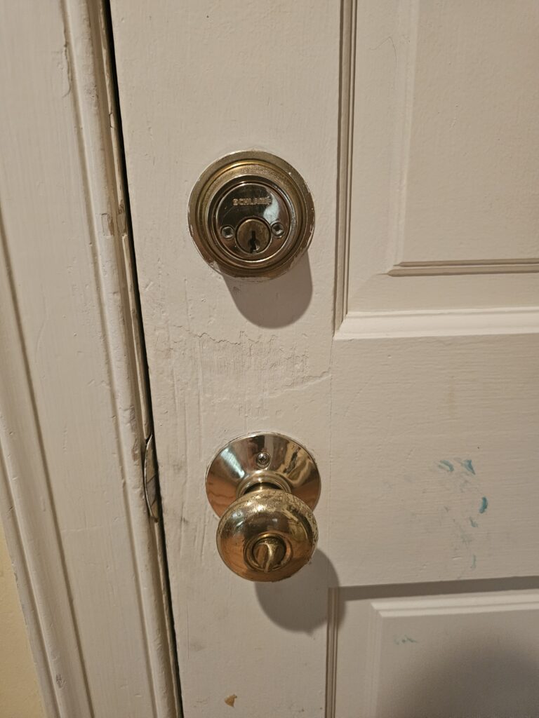 Close-up of worn doorknob and Schlage deadbolt on garage door