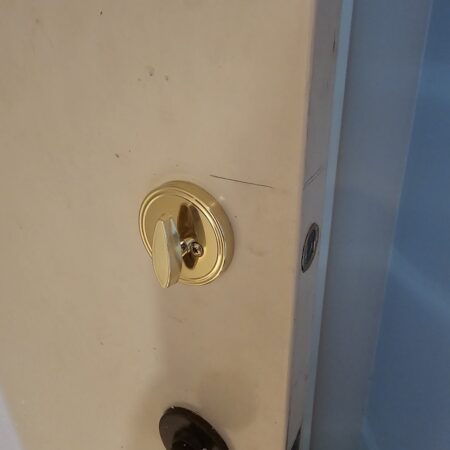 A newly installed brass deadbolt on a white residential door by a Memphis locksmith.