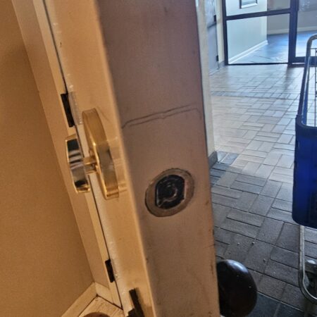 A brass deadbolt latch perfectly installed into the edge of a white door.