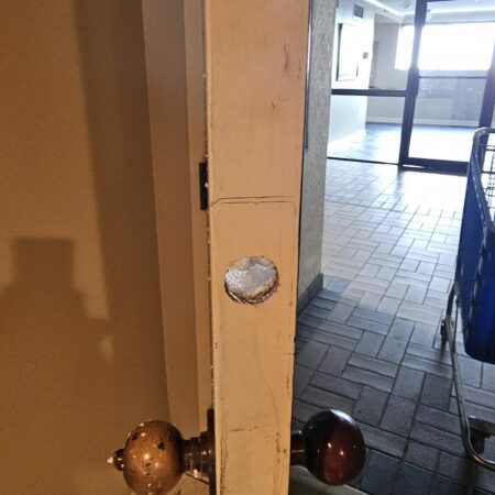 The edge of a commercial door freshly drilled for a new deadbolt latch by a local locksmith.