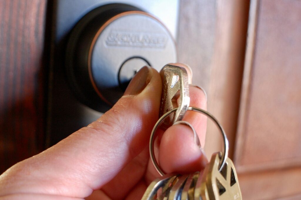 Hand unlocking dead bolt on door with set of keys