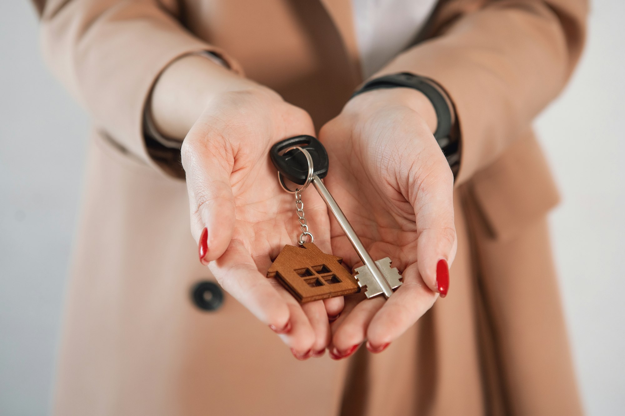 Woman hold keys with house keychain. Keys and house keychain in arms.