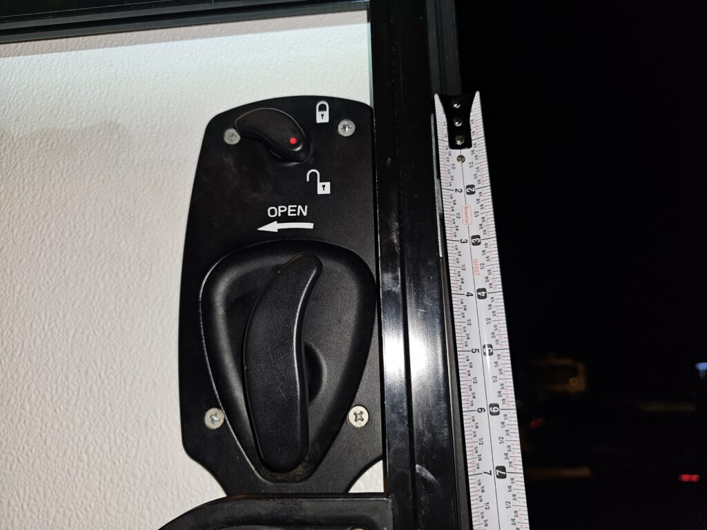Close-up view of interior RV camper door lock handle with measurement for locksmith rekeying.