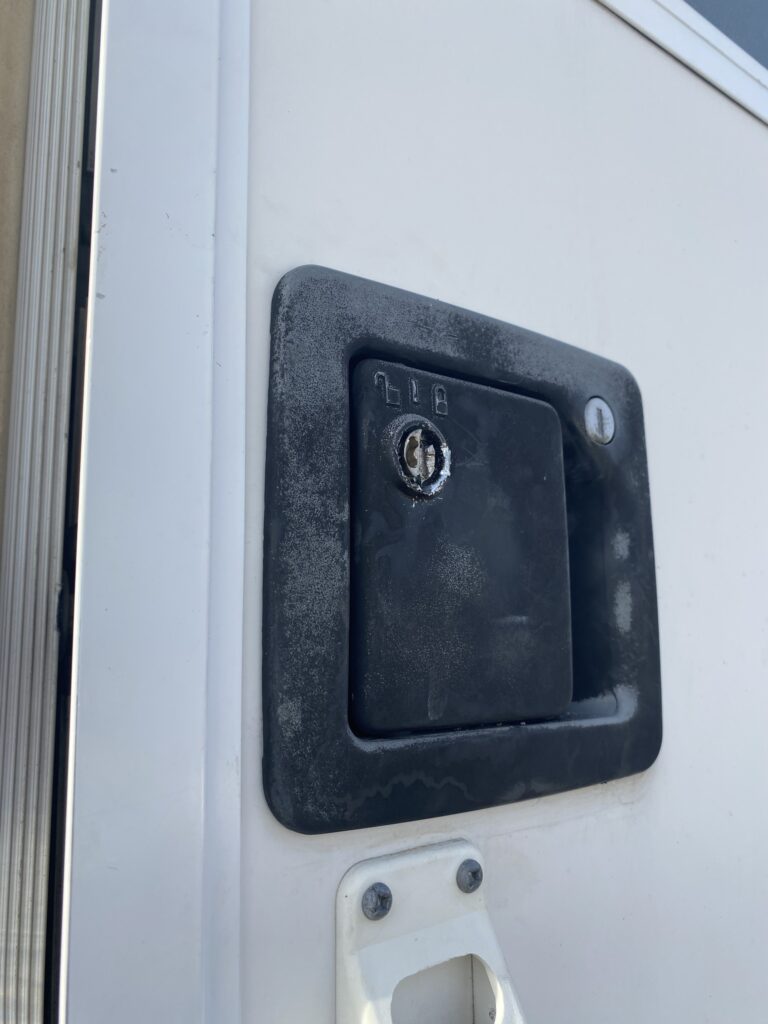 Damaged travel trailer door lock and handle ready for RV locksmith repair service.
