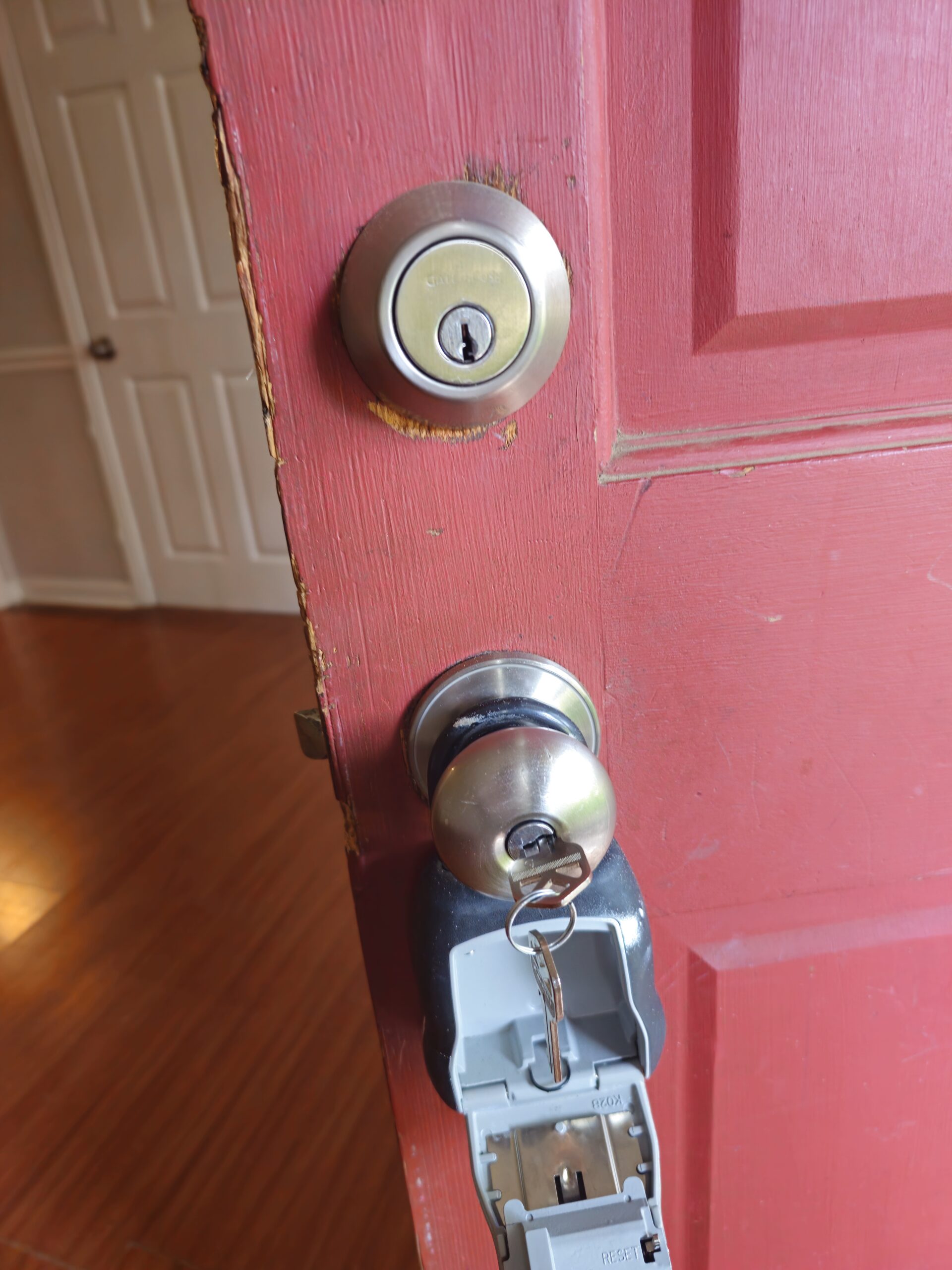 Rekeyed both the deadbolt and door knob showing a key turned into the cylinder and realtor lock box on red door