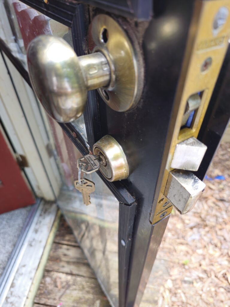 Close-up of storm door lock and brass knob with rekeyed keys